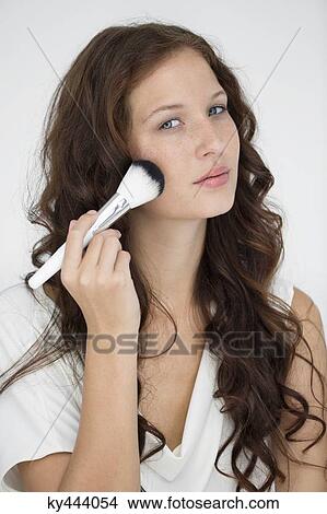 Portrait of a woman using make-up brush on face View Large Photo Image Picture - Portrait of a woman using make-up brush on face. Fotosearch