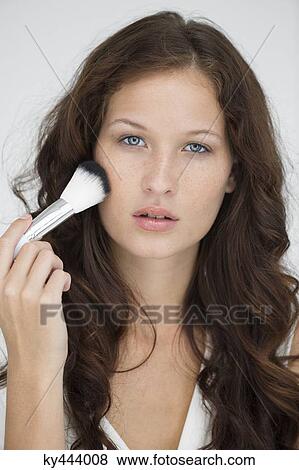 Portrait of a woman using make-up brush on face View Large Photo Image Stock Photo - Portrait of a woman using make-up brush on face. Fotosearch