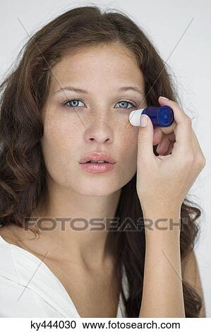 Stock Image - Woman applying anti wrinkle cream on her face. Fotosearch