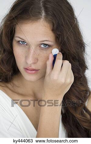 Stock Image - Woman applying anti wrinkle cream on her face. Fotosearch