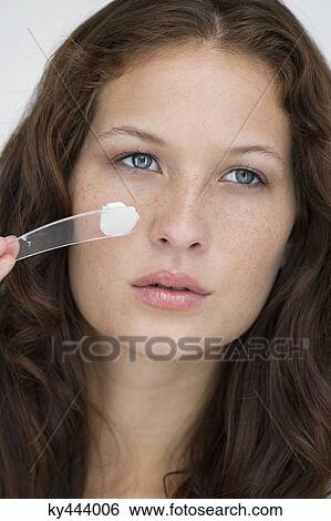 Woman applying moisturizer cream on her face View Large Photo Image Stock Photograph - Woman applying moisturizer cream on her face. Fotosearch