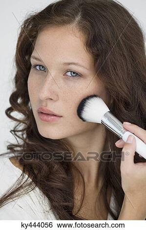 Stock Photograph - Woman doing make-up with a make-up brush. Fotosearch