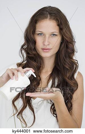 Stock Image - Woman pouring moisturizer on hand. Fotosearch