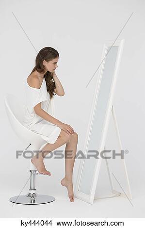 Woman sitting on a chair and looking at mirror View Large Photo Image Picture - Woman sitting on a chair and looking at mirror. Fotosearch