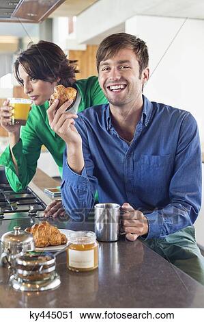 Couple having breakfast at a kitchen counter View Large Photo Image Stock Image - Couple having breakfast at a kitchen counter. Fotosearch