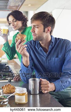 Stock Image - Couple having breakfast at a kitchen counter. Fotosearch