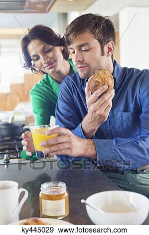 Couple having breakfast at a kitchen counter View Large Photo Image Stock Photo - Couple having breakfast at a kitchen counter. Fotosearch