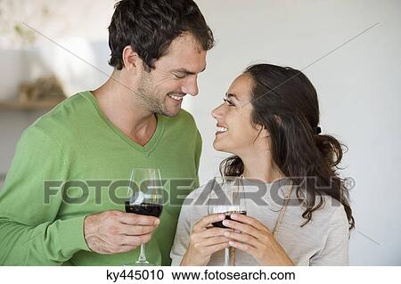 Stock Image - Couple holding wine glasses and smiling. Fotosearch