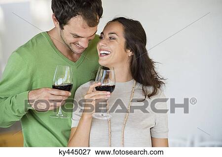 Stock Photo - Couple holding wine glasses and smiling. Fotosearch