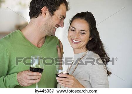 Stock Photo - Couple holding wine glasses and smiling. Fotosearch