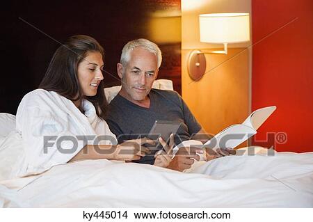 Couple looking at a digital tablet in a hotel room View Large Photo Image Picture - Couple looking at a digital tablet in a hotel room. Fotosearch
