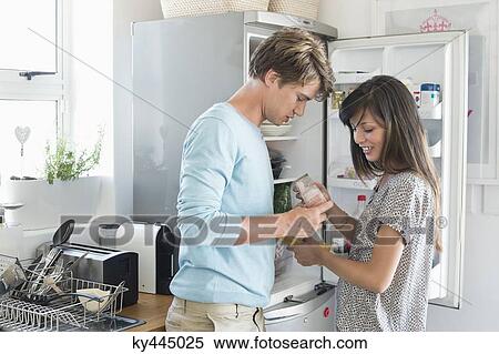 Couple looking at food product in front of a refrigerator in the kitchen View Large Photo Image Stock Photography - Couple looking at food product in front of a refrigerator in the kitchen. Fotosearch