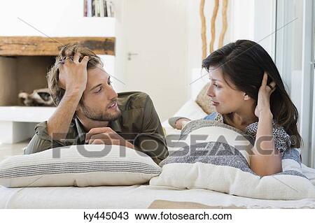Stock Image - Couple lying on the bed and looking at each other. Fotosearch