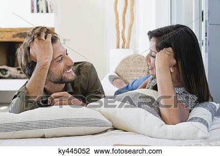 Stock Image - Couple lying on the bed and smiling. Fotosearch