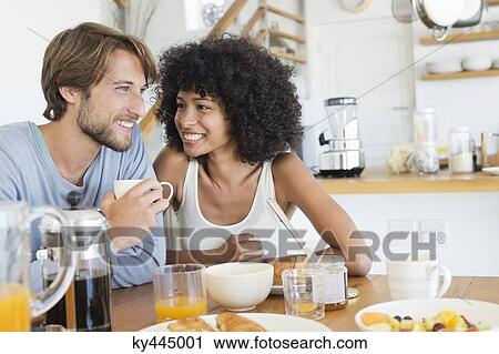 Couple sitting at a dining table having breakfast View Large Photo Image Stock Image - Couple sitting at a dining table having breakfast. Fotosearch