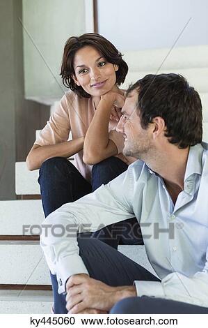 Stock Image - Couple sitting on stairs and smiling. Fotosearch