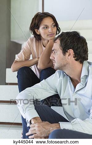 Picture - Couple sitting on stairs at home. Fotosearch
