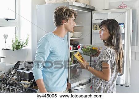 Couple talking in front of a refrigerator in the kitchen View Large Photo Image Stock Photography - Couple talking in front of a refrigerator in the kitchen. Fotosearch