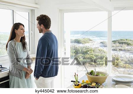 Stock Image - Couple talking to each other in the kitchen. Fotosearch