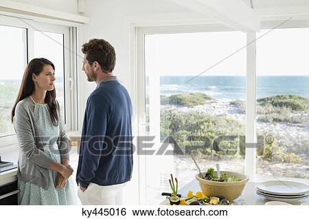 Stock Photograph - Couple talking to each other in the kitchen. Fotosearch