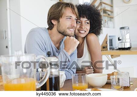 Stock Photograph - Smiling couple sitting at a dining table. Fotosearch