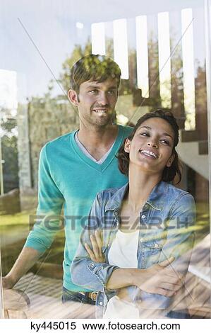 Smiling couple standing behind a glass wall View Large Photo Image Stock Photography - Smiling couple standing behind a glass wall. Fotosearch