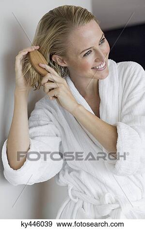 Stock Photo - Close-up of a smiling woman brushing her hair. Fotosearch