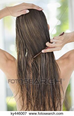 Stock Photo - Rear view of a woman combing her hair. Fotosearch