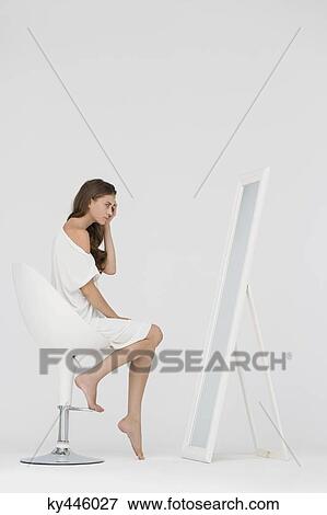 Woman sitting on a chair and looking at mirror View Large Photo Image Stock Photo - Woman sitting on a chair and looking at mirror. Fotosearch