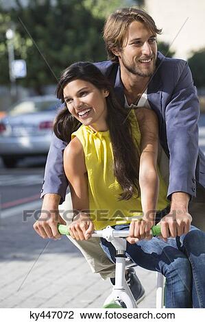 Couple riding a bicycle and smiling View Large Photo Image Stock Image - Couple riding a bicycle and smiling. Fotosearch