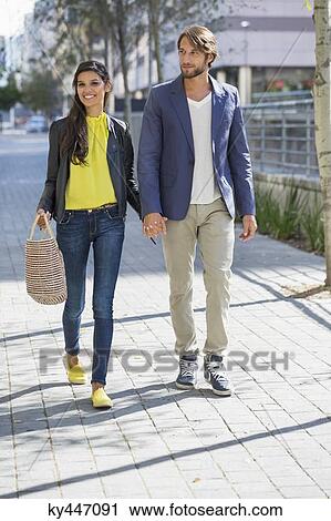 Stock Image - Happy couple walking on a street. Fotosearch