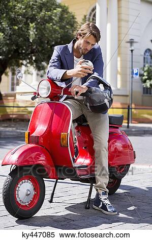 Man sitting on a scooter looking at a mirror View Large Photo Image Stock Photography - Man sitting on a scooter looking at a mirror. Fotosearch