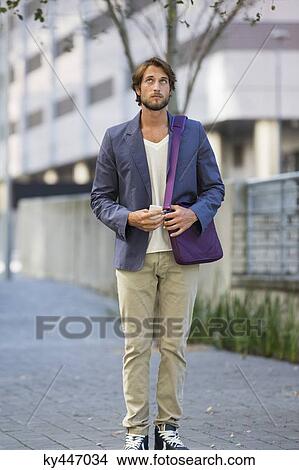 Picture - Man standing on a street looking up. Fotosearch