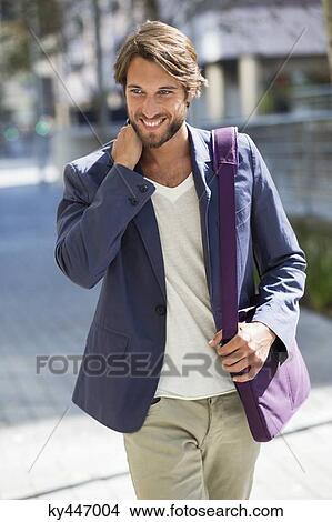 Picture - Man walking on a street and smiling. Fotosearch
