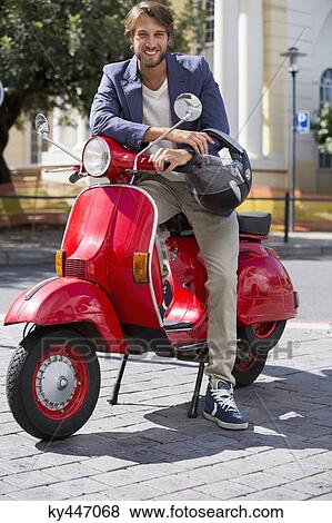 Stock Photo - Portrait of a man sitting on a scooter and smiling. Fotosearch