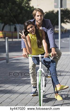 Portrait of a smiling couple riding a bicycle View Large Photo Image Stock Image - Portrait of a smiling couple riding a bicycle. Fotosearch
