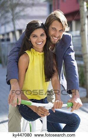 Portrait of a smiling couple riding a bicycle View Large Photo Image Stock Image - Portrait of a smiling couple riding a bicycle. Fotosearch