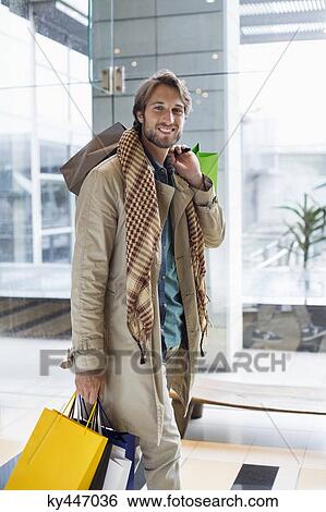 Portrait of a smiling man carrying shopping bags View Large Photo Image Stock Photograph - Portrait of a smiling man carrying shopping bags. Fotosearch
