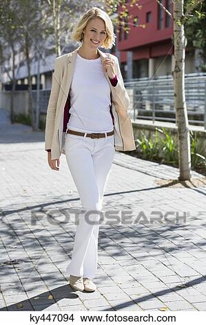 Picture - Portrait of a smiling woman walking on a street. Fotosearch