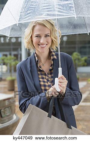 Portrait of a smiling woman with an umbrella View Large Photo Image Stock Photo - Portrait of a smiling woman with an umbrella. Fotosearch