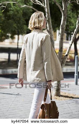 Picture - Woman walking on a street. Fotosearch