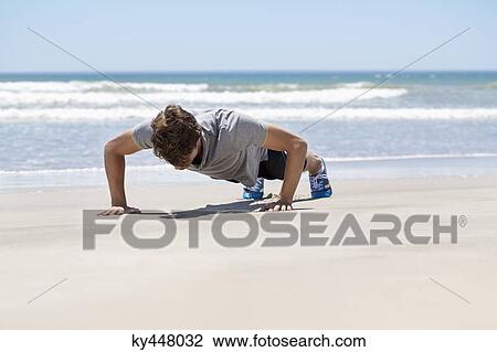 Stock Image - Man exercising on the beach. Fotosearch