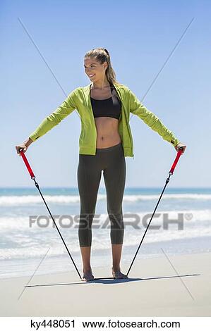 Smiling woman exercising with a chest expander on the beach View Large Photo Image Stock Image - Smiling woman exercising with a chest expander on the beach. Fotosearch