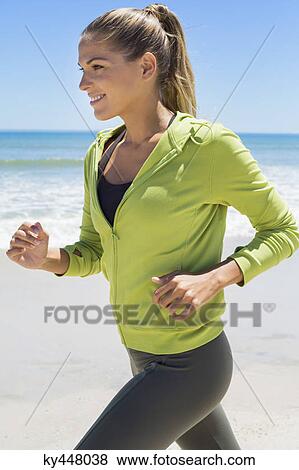 Stock Photo - Smiling woman running on the beach. Fotosearch