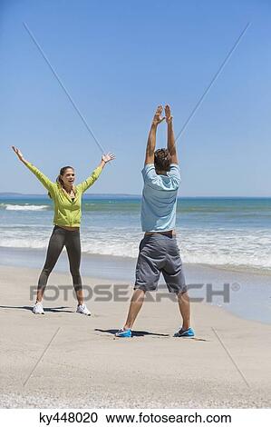 Stock Image - Woman and her coach exercising on the beach. Fotosearch