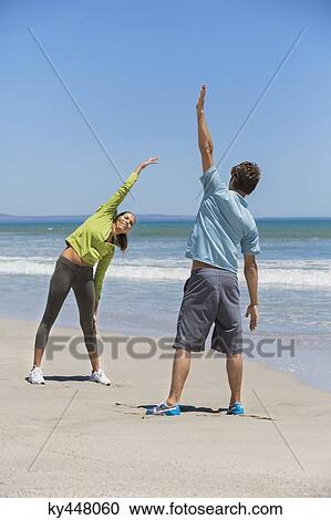 Stock Image - Woman and her coach exercising on the beach. Fotosearch