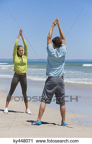 Stock Image - Woman and her coach exercising on the beach. Fotosearch
