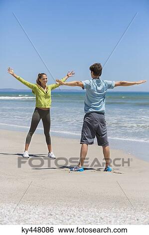 Stock Photograph - Woman and her coach exercising on the beach. Fotosearch