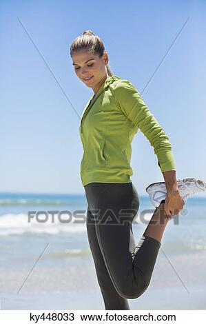 Stock Image - Woman exercising on the beach. Fotosearch