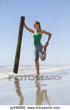 Stock Image - Woman exercising on the beach. Fotosearch